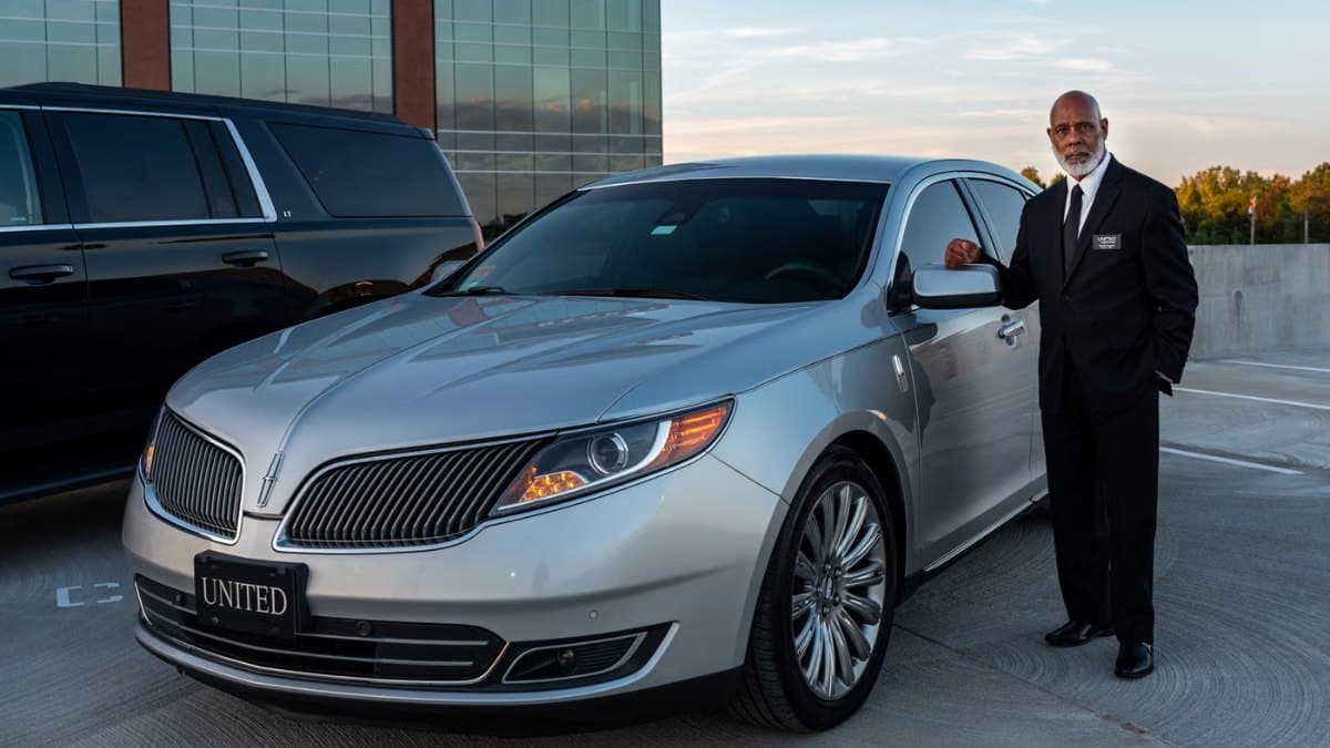 Professional chauffeur in a suit standing beside a luxury car outside a Toronto hotel