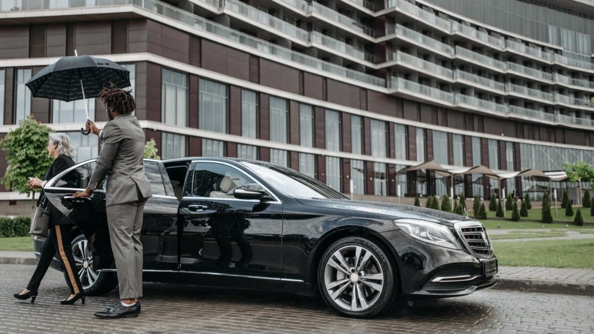 Business traveller stepping out of a chauffeured luxury car at a hotel entrance