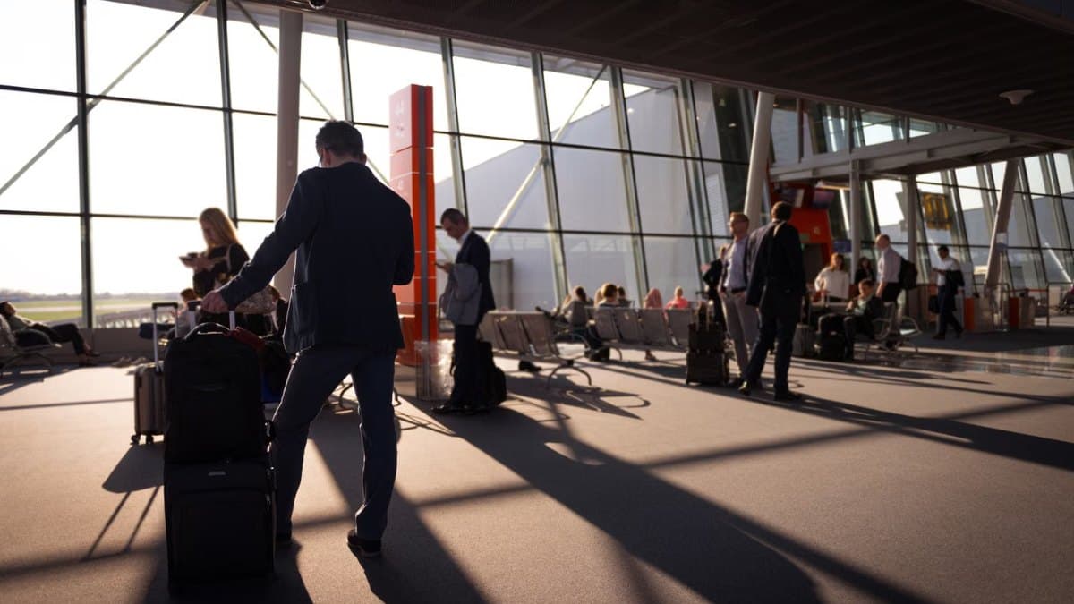 Travellers with luggage waiting in a busy airport terminal