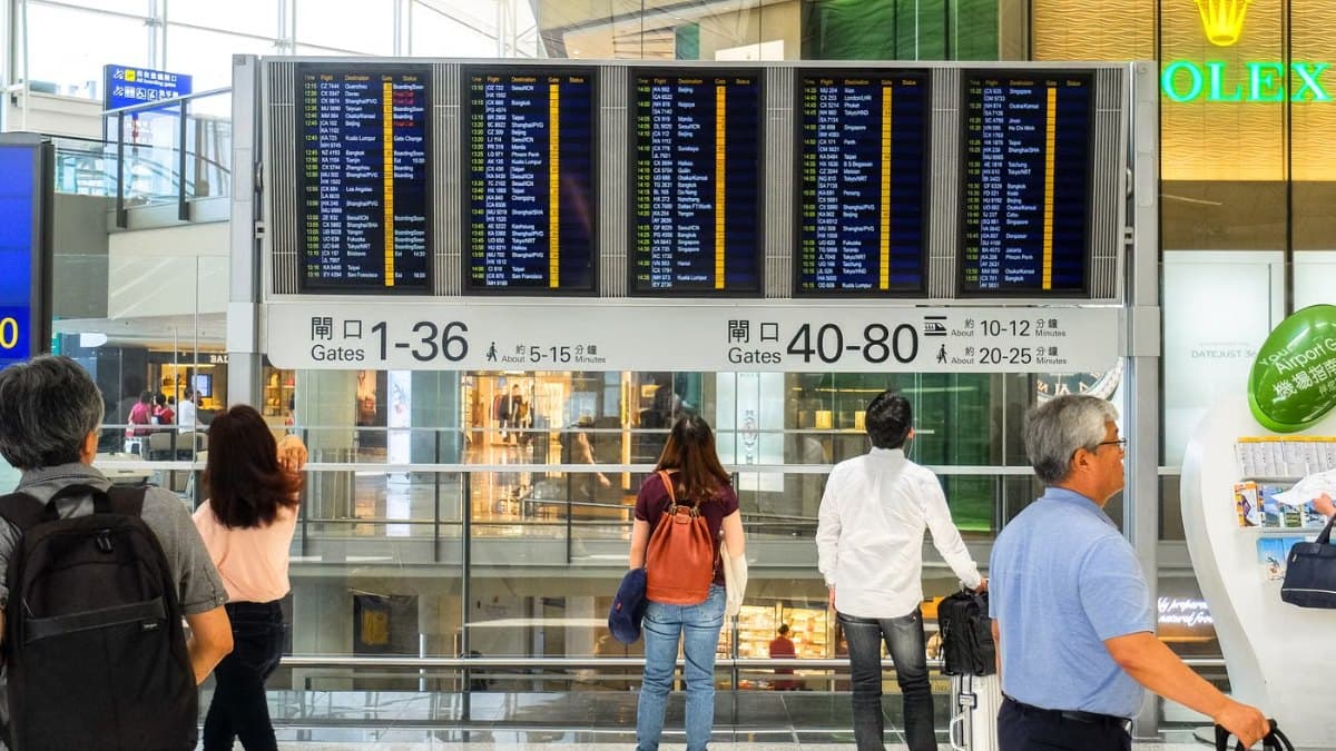 Passengers checking a departure board inside an international airport terminal
