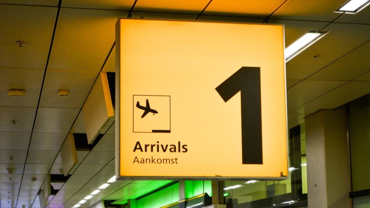 Bright arrivals sign with an airplane symbol inside an airport terminal