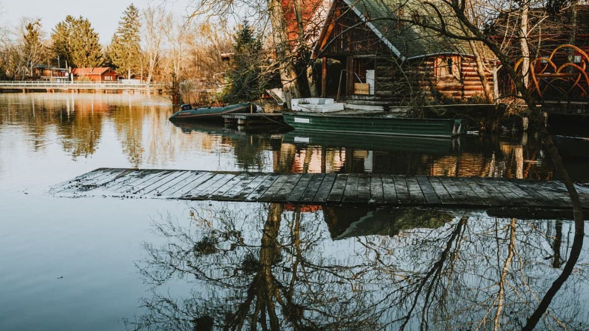 Rustic lakeside cabins and boats reflected in still water