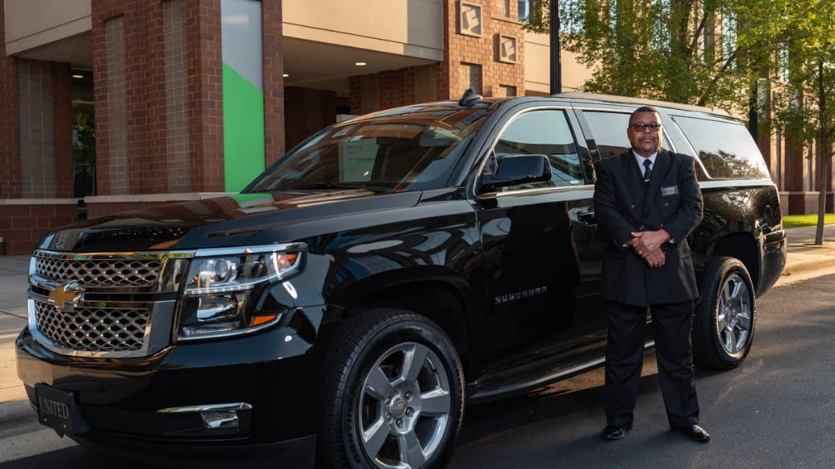 Chauffeur beside a black luxury car outside the Fairmont Royal York in downtown Toronto