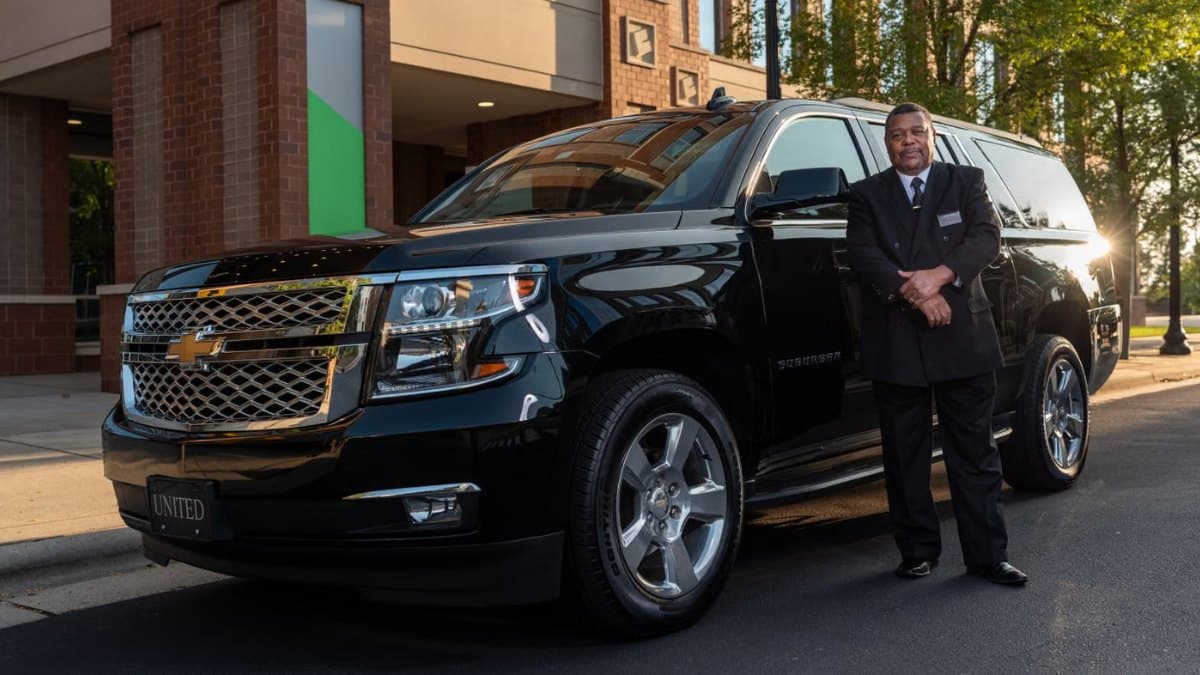 Chauffeur standing beside a black SUV offering luxury transfer service in Toronto