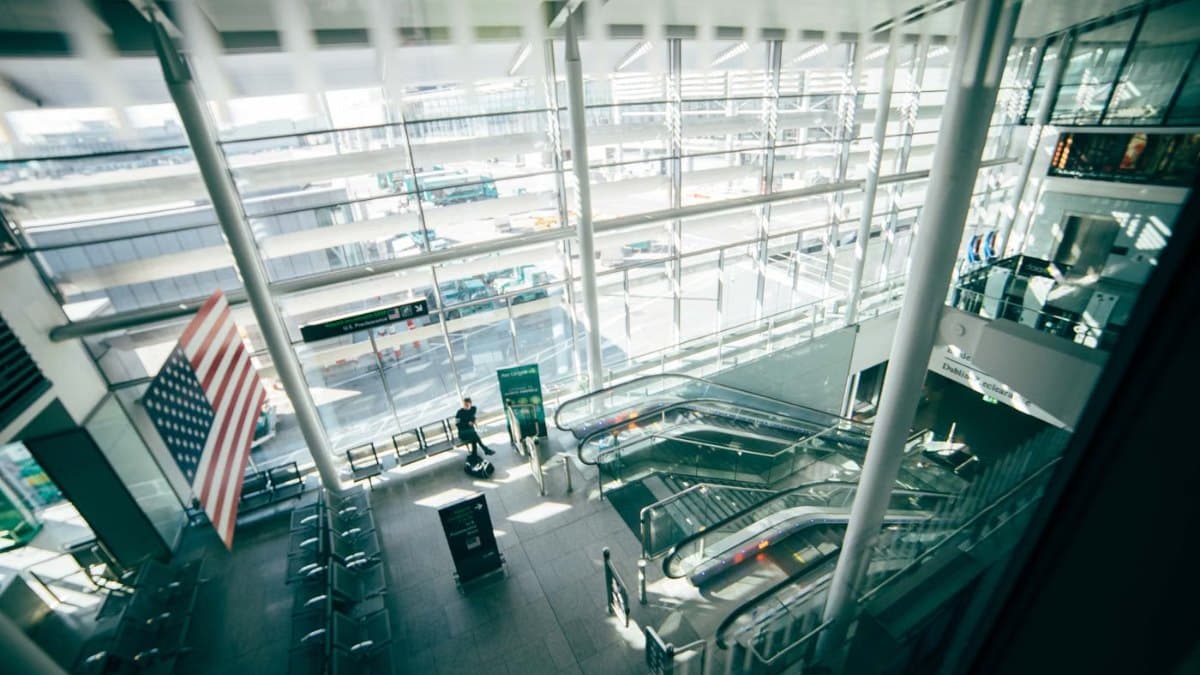 Bright modern airport terminal with glass walls and travellers arriving