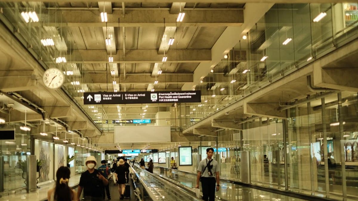 Passengers walking through a bright modern airport terminal with glass walls