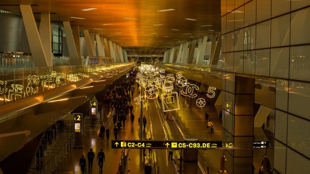 Busy modern airport terminal with vibrant lighting and travellers