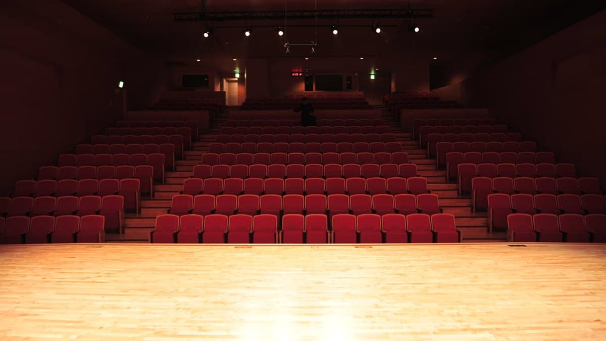 Theatre interior with rows of red seats and an illuminated stage