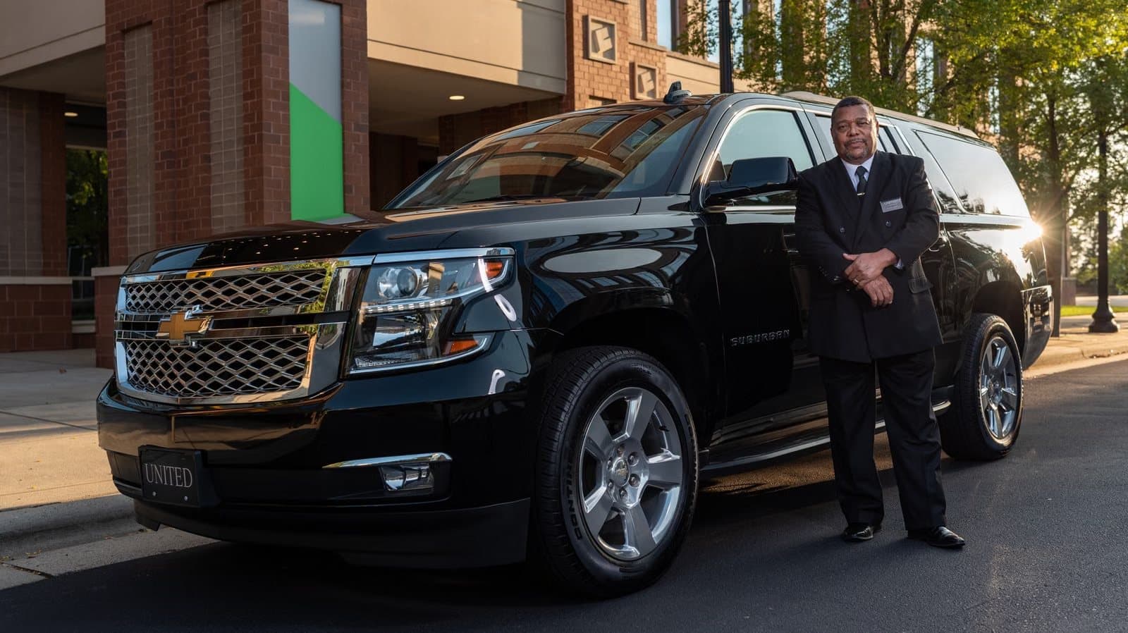 Chauffeur standing beside a black SUV ready for a hotel guest